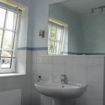 Bathroom with sink, mirror, and window with blinds.