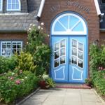 Blue entrance with arched window, surrounded by flowers and greenery.