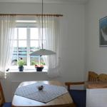 Dining room with wooden table, chairs, and window with white curtains.