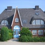 A two-story house with red brick and blue door. Roof with slate and windows.