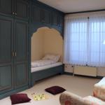 Zimmer mit integrierten Betten, Schränken und Fenster mit Vorhängen.