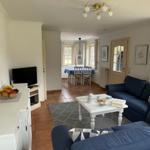 Wohn- und Essbereich mit blauem Sofa, weißem Tisch und Küchenzeile.