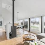 Living and dining area with wooden floor, large windows, and wood stove.