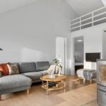 Living room with sofa, fireplace, and wooden floor. Upper level with balcony.