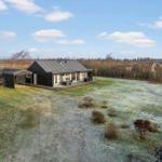 Modern villa with large garden and terrace under blue sky.