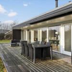 Deck with table, chairs, and sofa. Glass doors lead to interior.