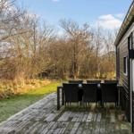 Deck with table and chairs next to a house with wooden siding.