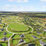 Aerial view of a holiday resort with many houses, green lawns, and a soccer field.