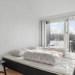 Bedroom with mattress, pillows, and sliding door to balcony.