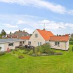 A house with a red roof and large garden with barbecue and seating area.