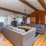 Wohnzimmer mit Holzboden, grauen Sofas und Kamin. Holzdecke mit Balken.