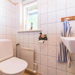 Badezimmer mit Toilette, Waschbecken und Fenster. Handtuch hängt an Wandhalter.