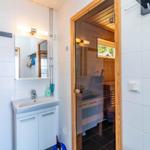Badezimmer mit Waschbecken und Dusche. Sauna im Hintergrund mit Holzwand.