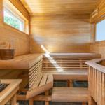 Holzsauna mit Sitzbänken, Fenstern und Steinen.