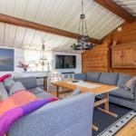 Wohnzimmer mit grauem Sofa, Holztisch und Holzwand. Fernseher und Wandbild sind sichtbar.