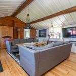 Wohnzimmer mit Holzboden, Sofa, Fernseher und Holzbalken an der Decke.