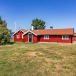 Rotes Holzhaus am See mit Garten und Schwimmbad.