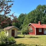Rotes Holzhaus mit weißen Fenstern und einer Terrasse. Neben einem kleineren gelben Gebäude mit roter Tür.