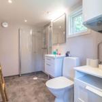 Badezimmer mit Dusche, Toilette und Waschbecken. Holzhandtuchhalter an der Wand.