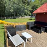 Terrasse mit Gartenmöbeln, gelbem Kanu und rotem Holzhaus mit Dach.