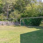 Grüner Rasenplatz mit zwei Fußballtoren und Steinmauer im Hintergrund.