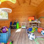 Holzvertäfelte Spielhütte mit bunten Spielzeugen und Kisten.