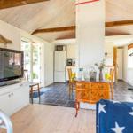Wohnbereich mit TV, Essbereich und Küche unter Holzdecke.