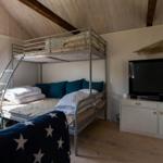 Zimmer mit Doppelstockbett, Fernseher und Fenster mit Blick nach draußen.