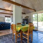 Essbereich mit Holztisch und Stühlen, dahinter Wohnbereich mit Sofa und Fernseher.