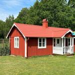 Rotes Holzhaus mit weißen Fensterrahmen und Veranda. Schwedische Flagge weht im Wind.