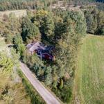 Rotes Haus in Wald und Feld, mit Waldweg und Parkplatz.