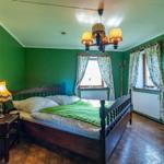 Schlafzimmer mit grünen Wänden, Holzbett und Kronleuchter.
