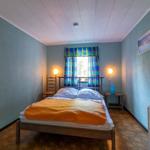 Schlafzimmer mit Bett, Fenster und Wandkarte.
