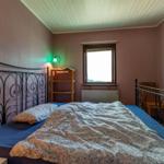 Schlafzimmer mit Metallbett, Fenster und Nachttisch mit Lampe.