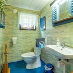 Badezimmer mit Toilette, Waschbecken und Fenster. Wände mit Muster, blauer Boden.