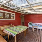 Terrasse mit Holzboden, Tisch, Bänken und roter Wand