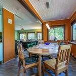 Essbereich mit Holztisch und Stühlen, Küche und Wohnzimmer im Hintergrund.