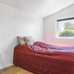 Schlafzimmer mit Bett, Fenster und Nachttisch mit Lampe.