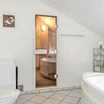 Bathroom with shower, toilet, and bathtub. Sauna with wooden wall in background.