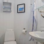 Bathroom with toilet, sink, and mirror. Wall decor with picture and towel.