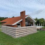 A house with a red roof and wooden fence. A large chessboard is on the property.