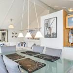 Dining area with glass table and gray chairs. Kitchen with wooden cabinets and white walls.