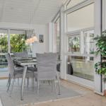 Dining room with glass top, gray chairs, and potted plant against wall.