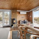 Esszimmer mit Holzdecke, Kamin und großem Fenster. Tisch mit Stühlen und Spielzeug.