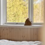 Ein Bett mit weißer Bettwäsche vor einem Fenster mit Blick auf Bäume.