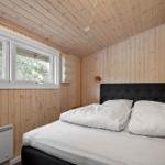Schlafzimmer mit Holzwand, Bett, Fenster und Wandleuchten.
