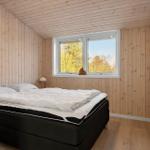 Schlafzimmer mit Holzwand, Bett und Fenster mit Blick auf Bäume.