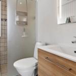 Badezimmer mit Dusche, Toilette und Waschbecken mit Spiegel.
