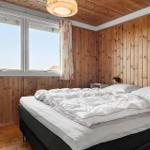 Schlafzimmer mit Holzwand, großem Fenster und Bett mit weißer Bettwäsche.