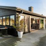 Moderne Holzhütte mit Terrasse, Glastüren und Sitzgelegenheiten im Freien.